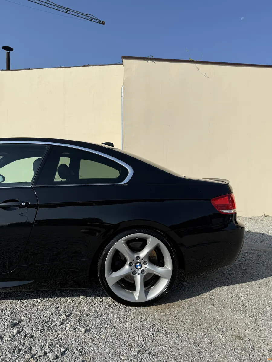 Czarne BMW coupe zaparkowane bokiem, zbliżenie na tylne koło