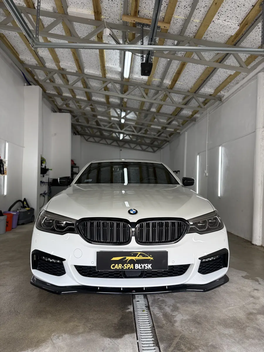 Białe BMW serii 5 w hali, ujęcie od przodu