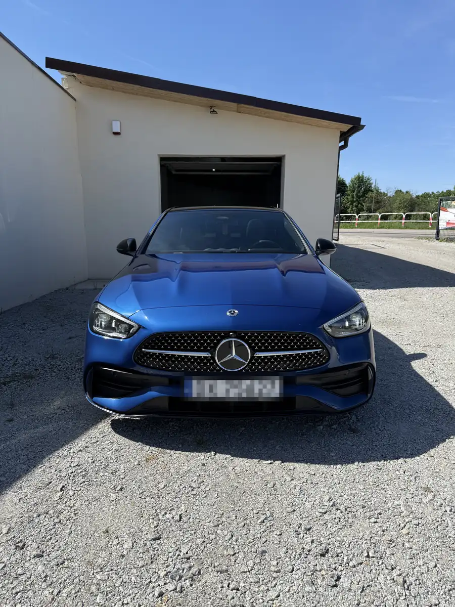 Niebieski Mercedes klasy C przed halą, ujęcie od przodu